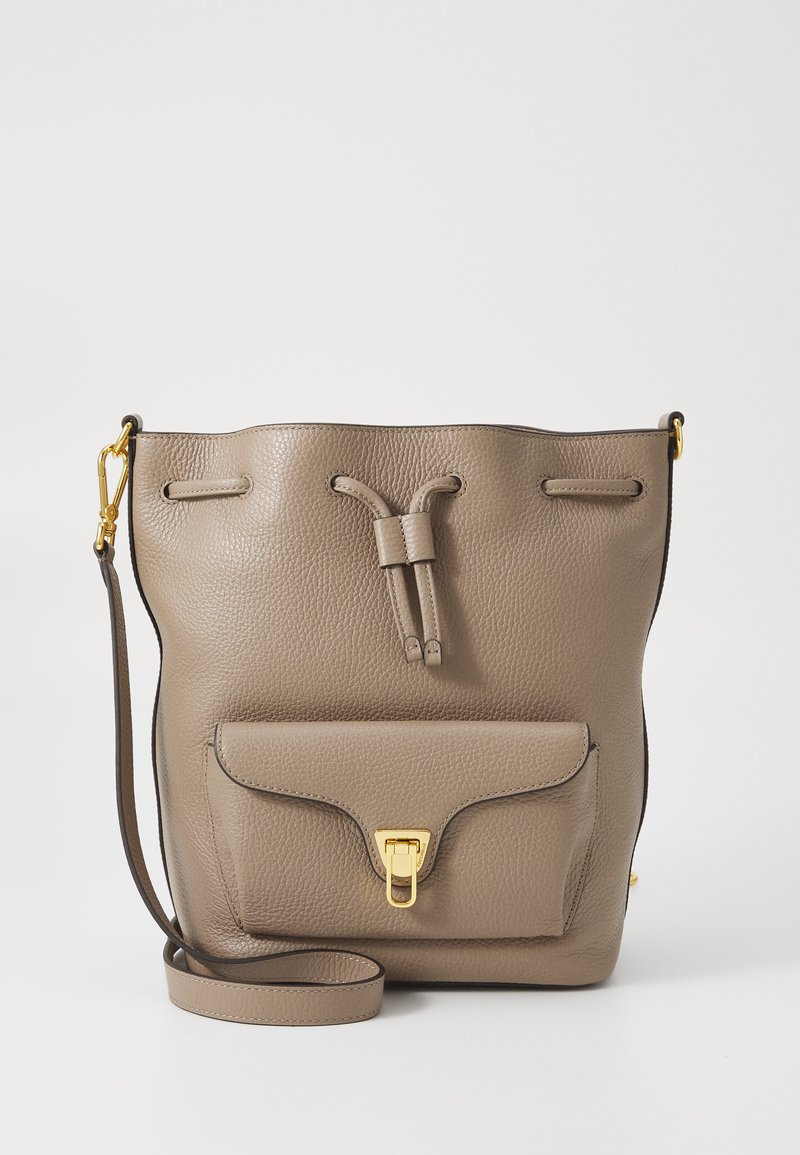 Borsa a secchiello in pelle tan con superficie testurizzata, chiusura a cordoncino, tasca frontale con patta e dettagli in hardware dorato. Tracolla regolabile.