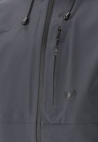 Herrjacka i mörkgrå nyans, av mjukt, vattenavvisande material. Har en framdragkedja, sidficka och logodetalj. Slät yta och justerbar huva.