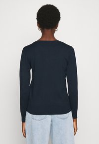 Marineblauwe lange mouw trui van gebreid materiaal met een iets aansluitende silhouet en geribbelde manchetten en zoom. Eenvoudig ontwerp, zonder patronen.