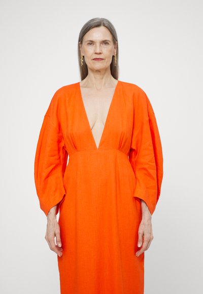 Orange linen dress with deep V-neck and wide sleeves, featuring a relaxed fit and smooth texture. Simple design without notable patterns.