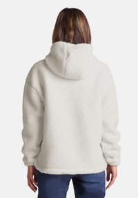 White fleece hoodie with a textured surface, large hood, and loose fit. Features long sleeves and a straight hem.