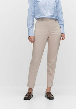 Beige maßgeschneiderte Hosen mit einer figurbetonten Passform, glatter Textur und schlanker Silhouette, kombiniert mit einem gestreiften blauen Hemd und braunen Mokassins.