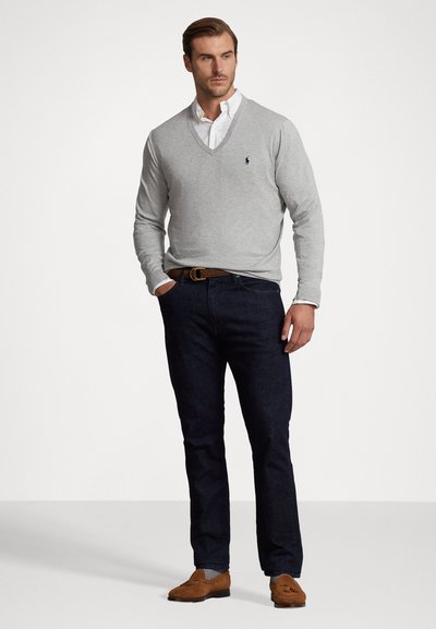 Light gray v-neck sweater with ribbed cuffs, navy jeans, and brown suede moccasin shoes. White button-up shirt beneath the sweater.