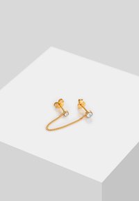 Pendientes en tono dorado con eslabones de cadena, decorados con piedras preciosas transparentes en cada arete. Superficie lisa, diseño minimalista.