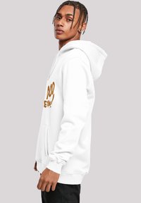Sudadera blanca con un bolsillo frontal, cordones y un gran gráfico de texto marrón. Presenta puños y cintura acanalados para un ajuste ceñido.