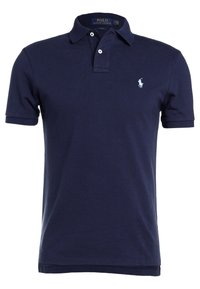 Granatowa koszulka polo wykonana z bawełny; posiada klasyczny kołnierzyk, pliskę z dwoma guzikami oraz małą haftowaną logo po lewej stronie klatki piersiowej.