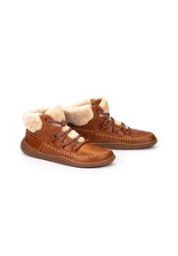 Botas de tobillo de cuero marrón con un suave forro de imitación de piel de oveja beige, puntera redondeada y cordones oscuros en contraste. Detalles de costura en los bordes.
