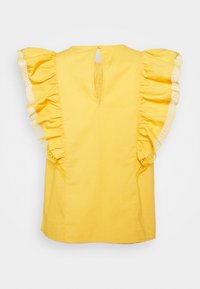 Gul ärmlös blus med volangärmar som har spetskanter och en liten knapp stängning bak i nacken.