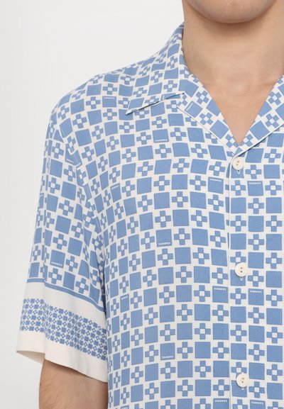 Cămașă cu mânecă scurtă, de culoare albastru deschis, cu un model geometric în pătrate, realizată dintr-un material moale. Detaliile din butoane albe și gulerul îmbunătățesc designul.
