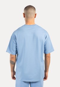 Helles blaues T-Shirt mit kurzen Ärmeln und lockerer Passform, aus weichem Stoff gefertigt, mit Rundhalsausschnitt und glatter Textur.