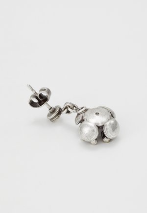 Clou d’oreille en argent avec un pendentif arrondi, texturé et en forme de petit animal, présenté sur un fond blanc uni.
