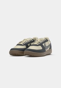 Sneakers con una tomaia in rete beige e sovrapposizioni in suede blu scuro, dotati di una suola in gomma con una superficie testurizzata e lacci beige.