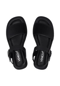 Zwarte sandalen met een gestructureerde, geribbelde band en een elegante enkelband met metalen gesp. Gladde voetbed met subtiele stikseldetails.