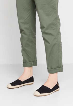 Flade sorte espadriller med rund tå og vævet jute-detalje rundt om sålen. Båret med opkrøllede olivengrønne bukser.