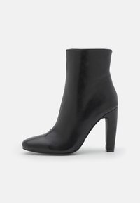Botín de cuero negro con un diseño elegante, punta afilada y un alto tacón de stilettos. Textura suave y sin herrajes visibles.