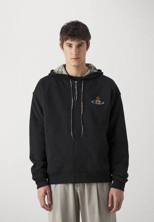 Haut à capuche noir zippé avec une poche avant et une doublure de capuche à motif. Présente un design brodé sur le côté gauche. Matériau doux.