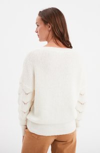Maglione spesso lavorato a maglia con una vestibilità morbida, caratterizzato da intagli a zigzag sulle maniche e orli e polsini a coste. Tessuto morbido, design casual.