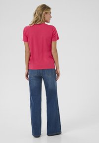 T-shirt ajusté à manches courtes en coton rose vif, associé à un jean bleu taille haute à jambes larges. Texture lisse, design décontracté.