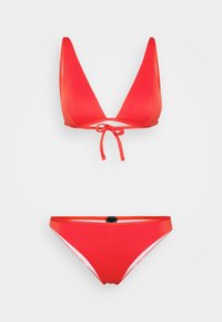 Crveni bikini set koji se sastoji od trokutastog vrha s vezanjem i odgovarajućih gaćica s bočnim akcentima u bijeloj boji. Glatki, rastezljivi materijal.