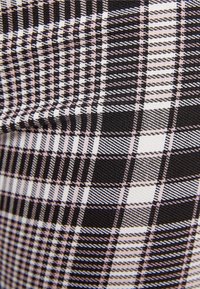 Czarno-biała tkanina w kratkę z różowymi akcentami. Charakteryzuje się mieszanką dużych i małych wzorów w kratkę, fakturowanym splotem i gładką powierzchnią.