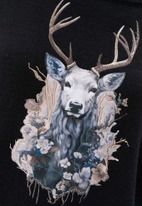 Czarna dzianina z haftem przedstawiającym głowę jelenia z misternymi kwiatowymi detalami w odcieniach niebieskiego, szarego i kremowego, podkreślona metalicznymi włóknami.