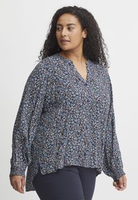 Námornícka kvietková blúzka vyrobená z ľahkej látky, s v-výstrihom, dlhými rukávmi a elastickými manžetami. Kvetinový vzor v odtieňoch modrej a bielej.