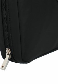 Bolsa negra de nylon con una textura suave, presenta un tirador de cremallera de metal plateado y un diseño aerodinámico.