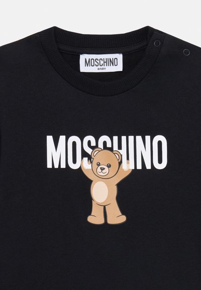 Schwarzes Baumwoll-T-Shirt mit einem Bär-Graphic, der die Arme hebt, und dem Text "MOSCHINO" in fetten weißen Buchstaben darüber. Druckknöpfe an der Schulter.