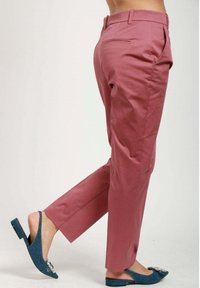 Rosa skräddarsydda byxor med slim fit, framfickor och en mjuk textur. Kombinerat med en blå slingback-sko med utsmyckningar.