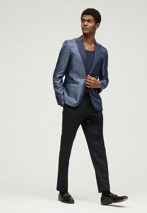 Blazer in navy with a textured pattern, featuring a satin shawl collar; paired with black tailored trousers and leather shoes.
