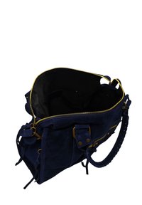Sac à main en suède bleu marine avec fermeture éclair dorée, extérieur texturé et poignée tressée. Intérieur noir, avec un design à ouvert.