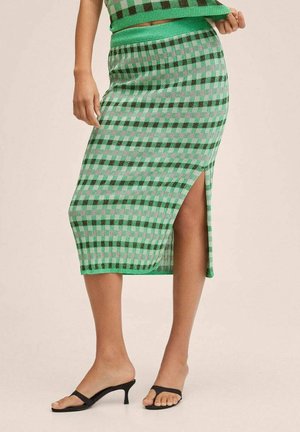 Groen-zwart geruite midi-rok met zijsplit, gecombineerd met een bijpassende cropped top en zwarte open-toe haksandalen.