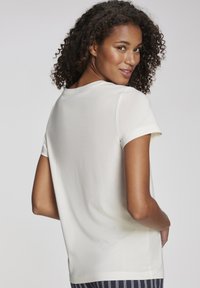 Krämfarbenes T-Shirt mit kurzen Ärmeln, rundem Halsausschnitt, lässiger Passform und weicher Textur. Verfügt über ein einfaches Design und dezente Nahtdetails.