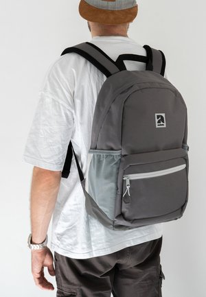 Sac à dos en tissu gris avec un compartiment principal et une poche avant. Doté d'une pochette latérale en maille et de bretelles noires ajustables. Design simple avec logo.
