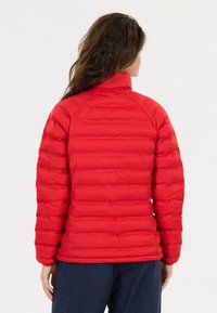 Rode pufferjack met een verticaal gequilt ontwerp, hoge kraag en een gestructureerde afwerking. Heeft nauwsluitende mouwen en een rechte zoom.