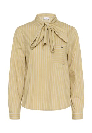 Blouse beige à manches longues avec des rayures verticales blanches, un grand nœud papillon au col et une poche plaquée boutonnée sur la poitrine.