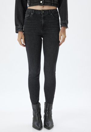 Jeans skinny noirs avec une taille haute, en denim. Dotés de poches avant, d'un zip et de coutures élégantes. Associés à des bottines noires.
