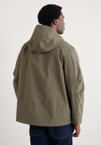 Veste à capuche vert olive avec une coupe décontractée, dotée de rayures verticales subtiles et d'accents aux épaules, confectionnée en tissu léger.