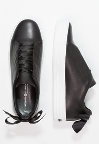 Sneakers in pelle nera con una finitura liscia, punta arrotondata e suola in gomma bianca. Presentano una chiusura con lacci e un accento in nastro di raso nero.