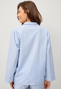 Gestreepte pyjamablouse in lichtblauw en wit, met lange mouwen en een klassieke kraag. Gemaakt van zachte katoenstof met een ontspannen pasvorm.