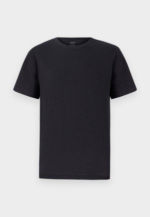 Must must have pehmeast, kergest kangast, klassikalise ümar kaeluse ja lühikeste varrukatega. Lihtne, ühetimeline disain ilma mustrite või aksessuaarideta.