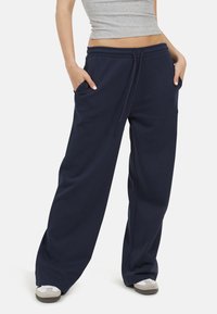 Pantaloni da ginnastica a gamba larga di colore blu navy, con vita elasticizzata, cordino e tasche laterali. Realizzati in un morbido tessuto testurizzato.