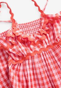 Roosa ruuduline kleit volangidega ääristuse ja reguleeritavate rihmadega. Omadused hõlmavad paeltega soonikuga ülakeha ja pehmet puuvillast tekstuuri.