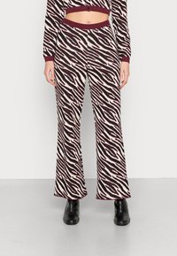 Calças largas com padrão de zebra em uma mistura de cores creme, preto e bordô. Tecido de malha macio com cintura canelada.
