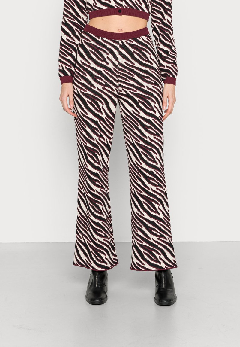 Calças largas com padrão de zebra em uma mistura de cores creme, preto e bordô. Tecido de malha macio com cintura canelada.
