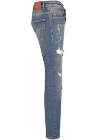Slim-fit sinised teksad, pleekinud kulumisdetailide ja rebenenud kohtadega. Taga on pruun nahkplekk vööl ja traditsioonilised taskud.