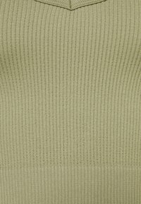 Ribbed knit top light greenissä; siinä on V-mallinen kaula-aukko ja tekstuuripinta. Pehmeä, joustava kangas, joka istuu hyvin.