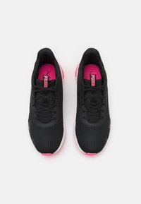 Zwarte sportieve schoenen met een bovenwerk van mesh, roze accenten op de binnenzolen en buitenzolen, en zwarte veters. Vlak, rond te ontwerp met een lichte hak.