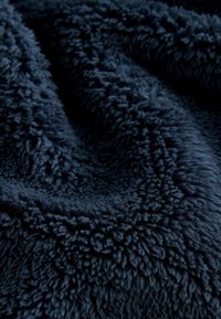 Coperta soffice blu navy con una superficie testurizzata e alta. Presenta un tessuto morbido e peloso che appare caldo e accogliente.