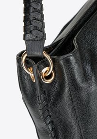 Zwarte leren handtas met een gestructureerde afwerking, voorzien van een gevlochten schouderband en goudkleurige ringhardware voor sluiting.